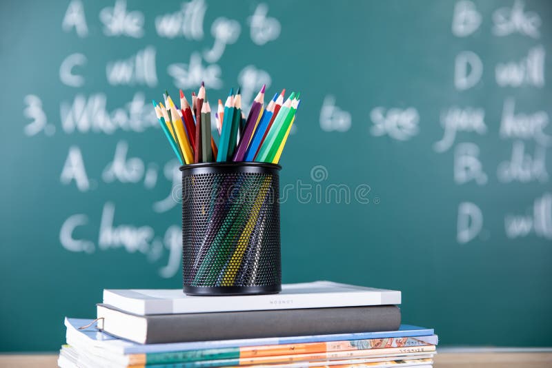 Black Pencil Holder Full of Colored Pencils on the Stack of Books Stock