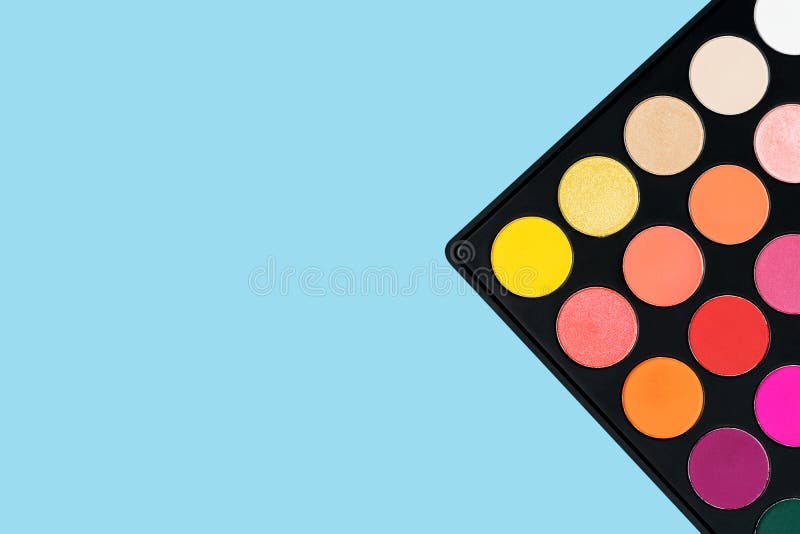 Black plastic palette of brightly coloured yellow, red, pink, orange eyeshadow placed in the corner of pastel baby blue background royalty free stock photos Black plastic palette of brightly coloured yellow, red, pink, orange eyeshadow placed in the corner of pastel baby blue background royalty free stock photos