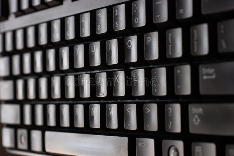 Black plastic standard English computer keyboard close up macro shot top side view.