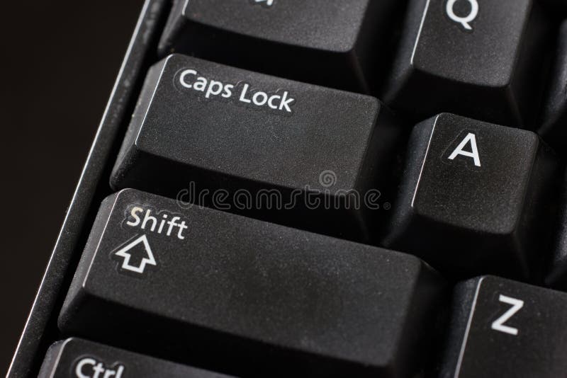 Black plastic standard English computer keyboard close up macro shot top side view Shift and Caps Lock buttons.