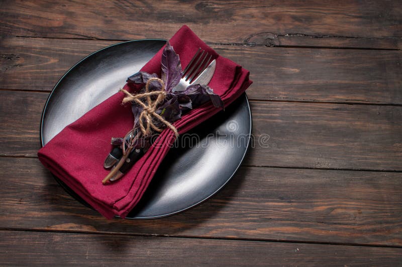 Black plate with fork,knife, napkin and basil on wooden table. royalty free stock images Black plate with fork,knife, napkin and basil on wooden table. royalty free stock images