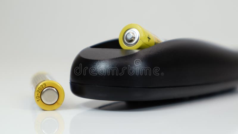 Black Remote Control with Yellow AAA Batteries on a White Background ...