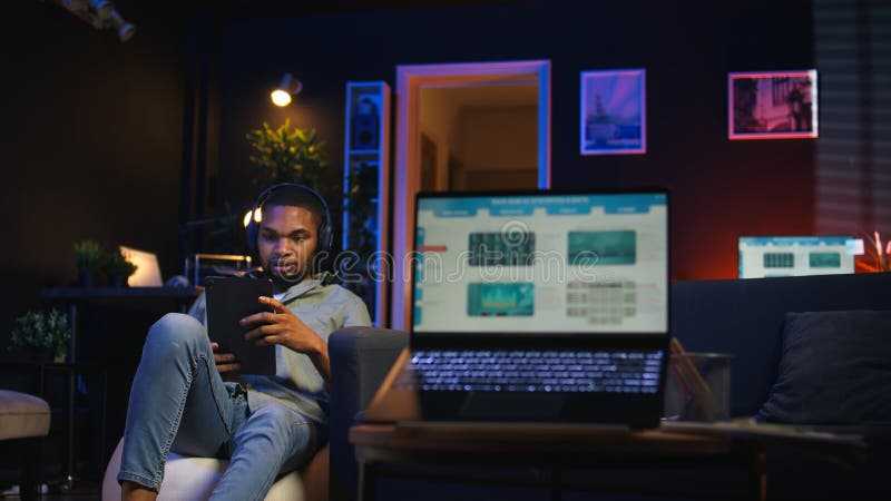 Black remote worker navigating on tablet next to screen running analytics royalty free stock photo