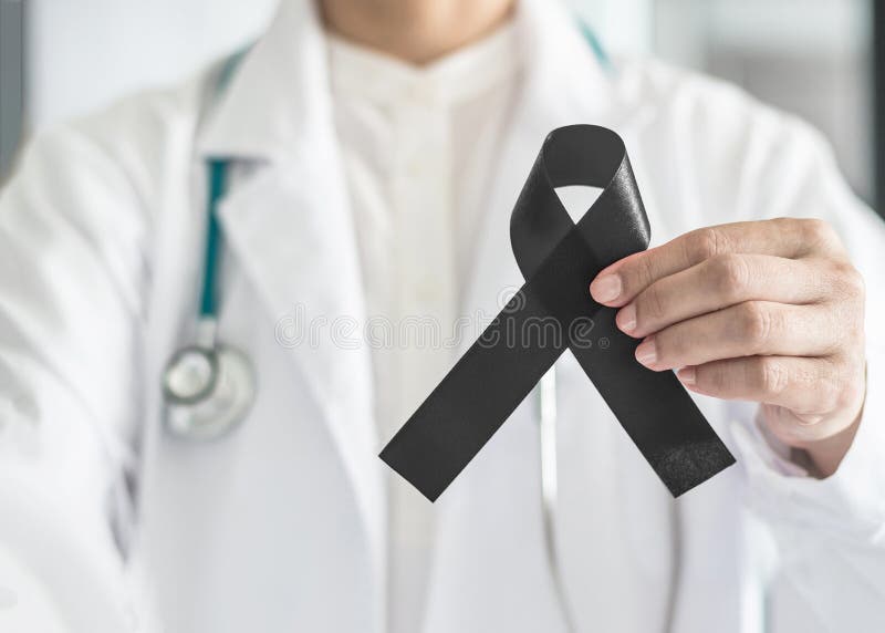 Black ribbon awareness in doctor`s hand for Melanoma and skin cancer, Narcolepsy, Primary Biliary Cirrhosis Cholangitis
