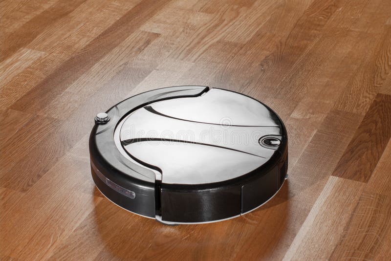 Black Robot Vacuum Cleaner On Parquet Floor Cleaning Dust In The