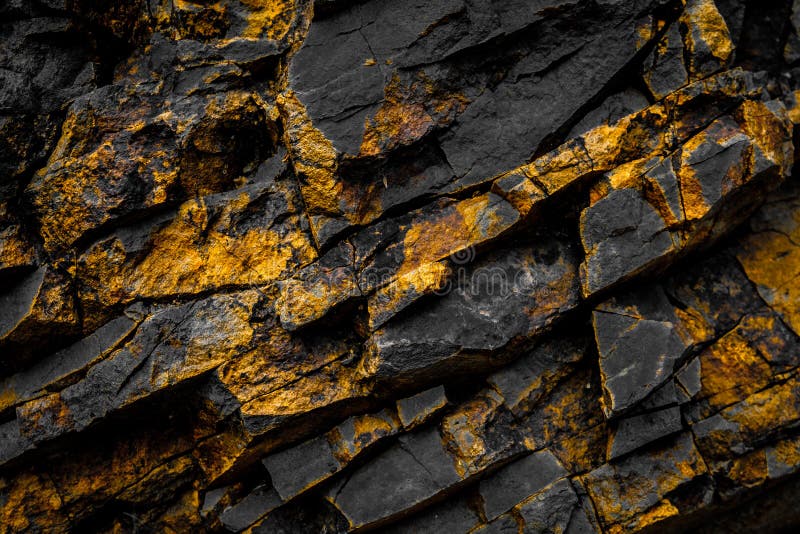 Black rock background with gold / yellow colored rocks stock photography
