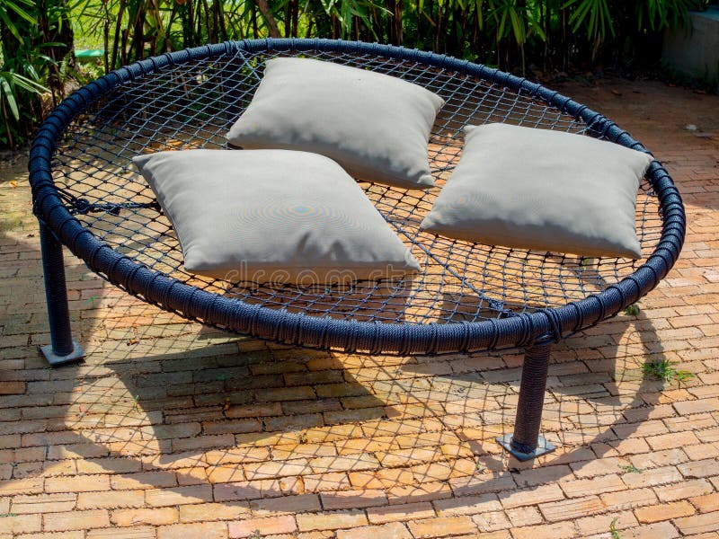 Black round macrame sofa bed on multiple ropes with three pillows in garden