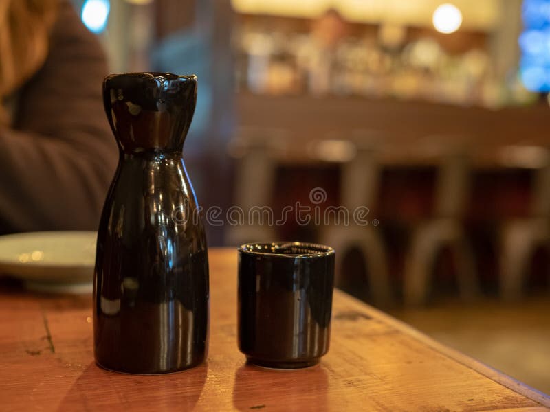 Black Sake Bottle and Glass Sitting on Table at Dining Area Stock Image