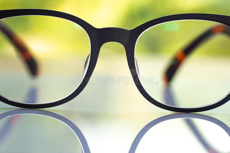 Black Shortsighted Or Nearsighted Eyeglasses On White Acrylic Table, Bokeh Green Garden Background, Close Up & Macro Shot,