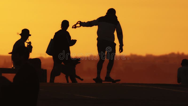 Black silhouettes of people on the hill at sunset - a man playing guitar