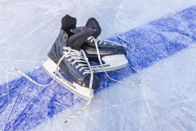 Black sports skates lie on a hockey rink on the blue line royalty free stock image Black sports skates lie on a hockey rink on the blue line royalty free stock image