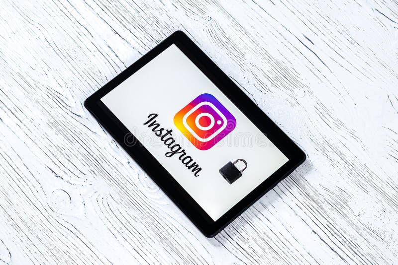 Black tablet computer on a white wooden table with a messenger instagram logo on the screen and lock. The concept of online security or resource locking