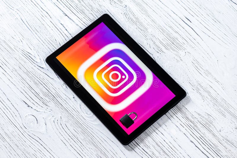 Black tablet computer on a white wooden table with a messenger instagram logo on the screen and lock. The concept of online security or resource locking