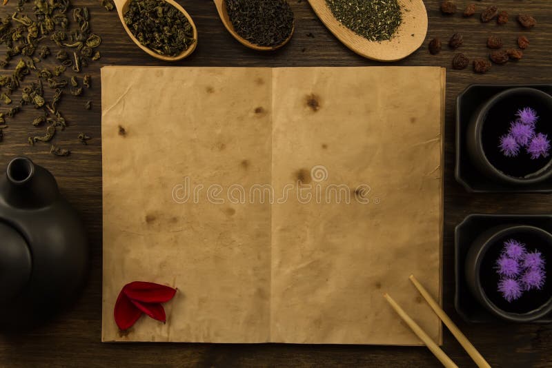 Black teapot, two cups, tea collection, flowers, old blank open book on wooden background. Menu, recipe