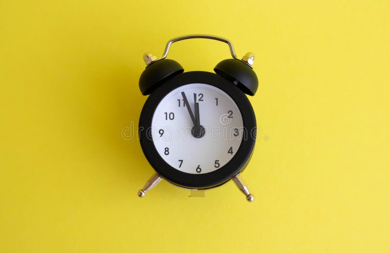 Black Vintage Alarm Clock Lying on a Yellow Backgroun Stock Image