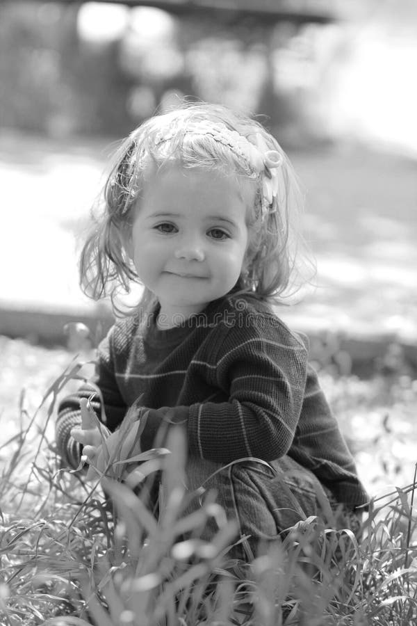 Black and white close up of extremely cute little one year old girl sitting in the grass royalty free stock images Black and white close up of extremely cute little one year old girl sitting in the grass royalty free stock images