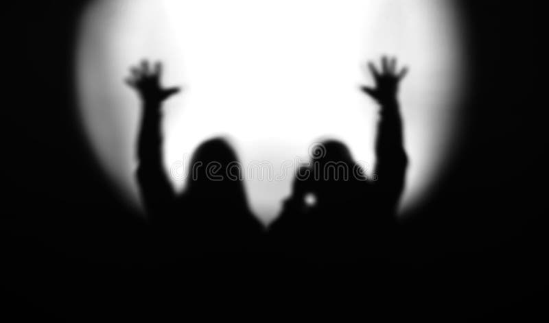 Black and white couple silhouettes with hands up in light of flo.