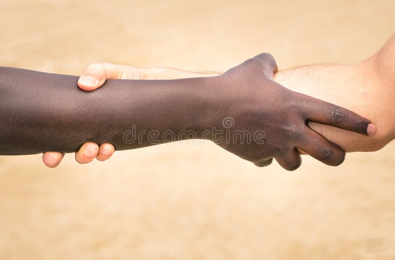 Black and white hands in modern handshake to show each other friendship and respect - Helping and respecting each other against racism - Slightly crispy detailed filtered look on defocused background. Black and white hands in modern handshake to show each other friendship and respect - Helping and respecting each other against racism - Slightly crispy detailed filtered look on defocused background