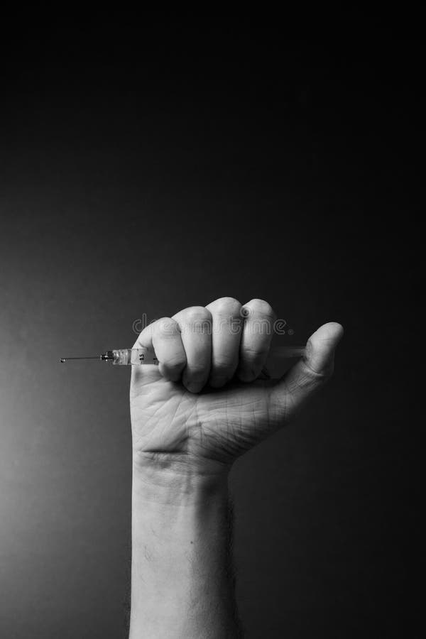 Man`s hand holding syringe with dramatic lighting royalty free stock images