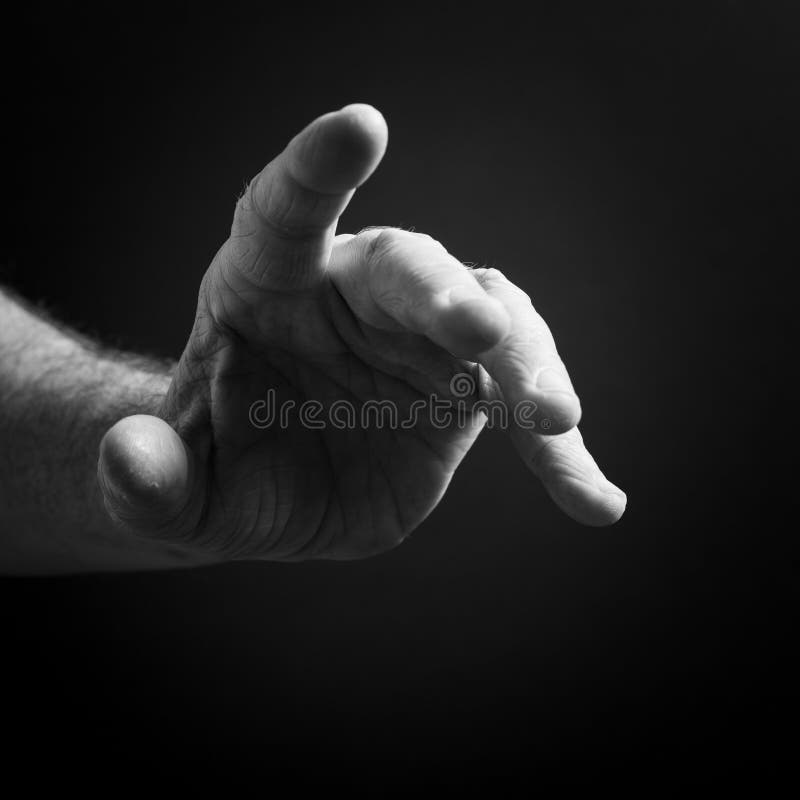 Black & white image of man`s hand pointing, isolated against a black background with dramatic sidelight royalty free stock photos