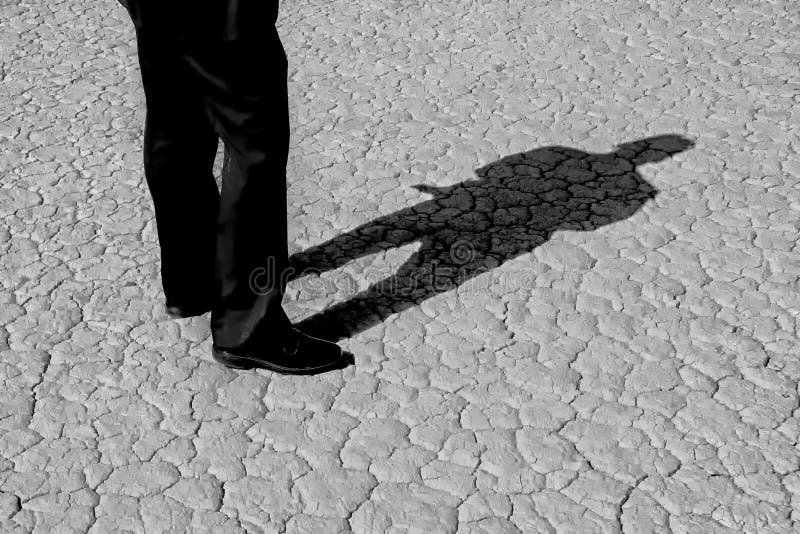 Black and White Image of a Man’s legs casting full body shadow on dry lake bed royalty free stock photos