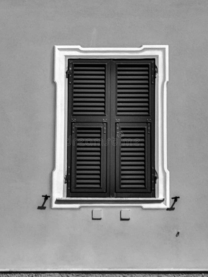 Black and White Photography of a Closed window with green sun-blinds on an orange wall