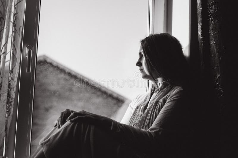 woman looking out window black and white