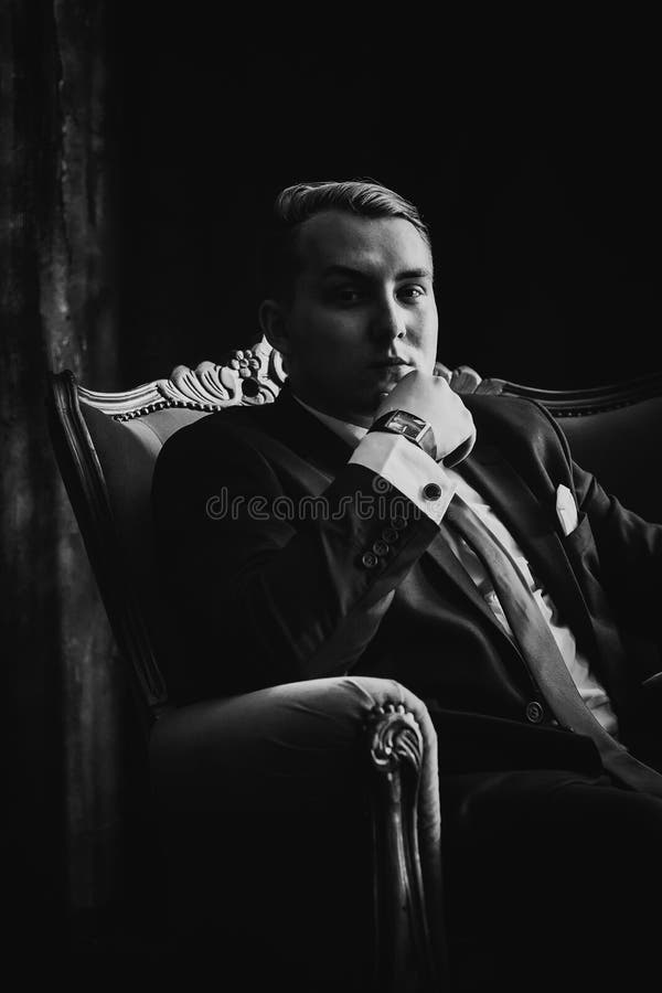 Black white photography portrait of man in black classic suit on a dark background. Beautiful, elegant.