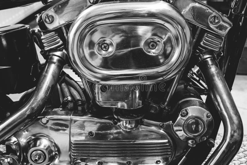 Black and white picture of fragment of v-twin engine in old-fashioned chopper. Chrome motor housing.