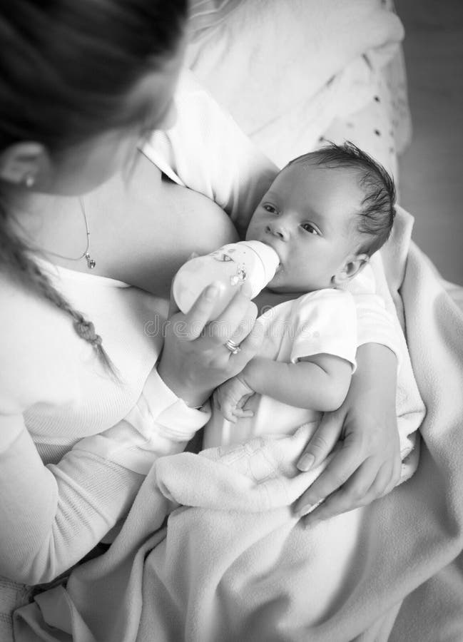 Black and white portrait of mother feeding baby with milk from b