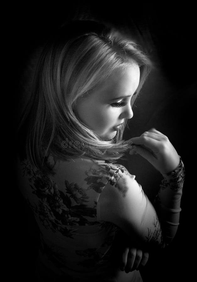 Black and white portrait of sensual blonde woman posing in dramatic natural light, wearing a floral top stock photo Black and white portrait of sensual blonde woman posing in dramatic natural light, wearing a floral top stock photo