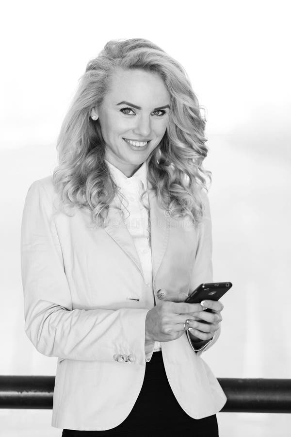 Black And White Portrait Of Smiling Woman Using Mobile Phone Stock