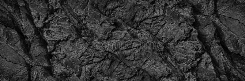 Black white rock texture. Dark gray stone wall background with space for design. Cracked rough mountain surface. Close-up. Wide ba