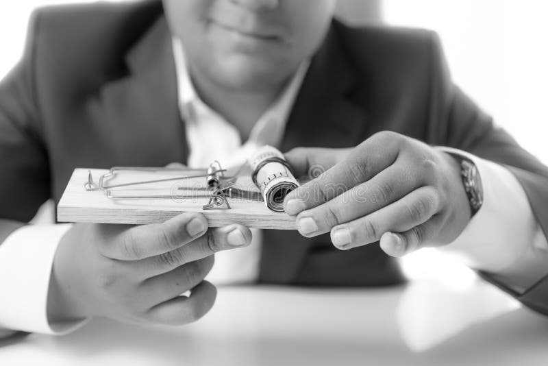 Black and white shot of businessman holding mousetrap with money