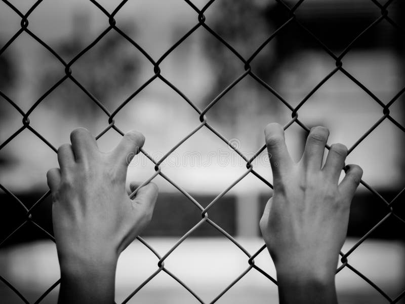 Black and white of Women Hands holding fence on outdoor scenery during daylight. Hand In Jail, concept of life imprisonment