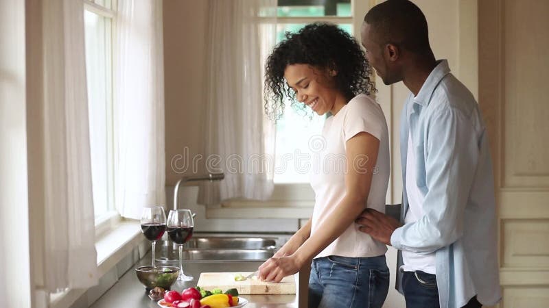 Wife prepares dinner husband embrace her behind talking enjoy date