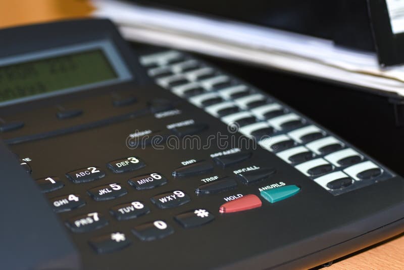 Black wire telephone with buttons and display on desk in office stock photography Black wire telephone with buttons and display on desk in office stock photography
