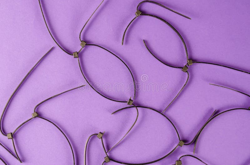 Black Wire Ties on Lilac Background. Old Cut Plastic Ties Stock Image