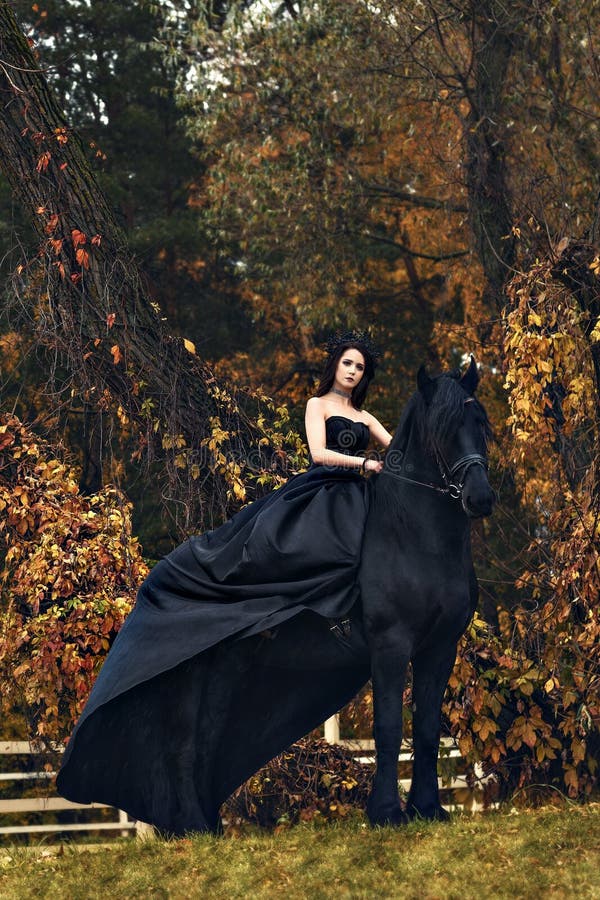 Black witch queen horseback on a black horse in a gloomy grim dark forest as in a horror scary fairy tale royalty free stock image Black witch queen horseback on a black horse in a gloomy grim dark forest as in a horror scary fairy tale royalty free stock image