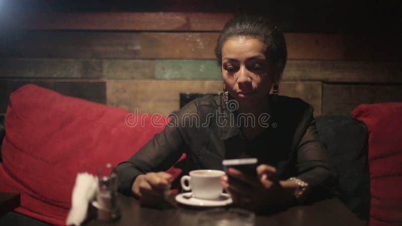 Black woman drinking hot coffee and use smartphones. Hot cafe video