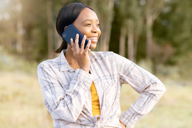 Black woman, forest and phone call for talking, thinking and smile on grass in summer sunshine. Adventure holiday, comic stock photography