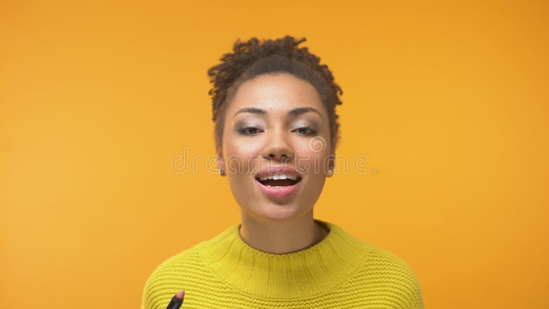 Black woman putting lipstick and sending air kiss to camera, enjoying outlook