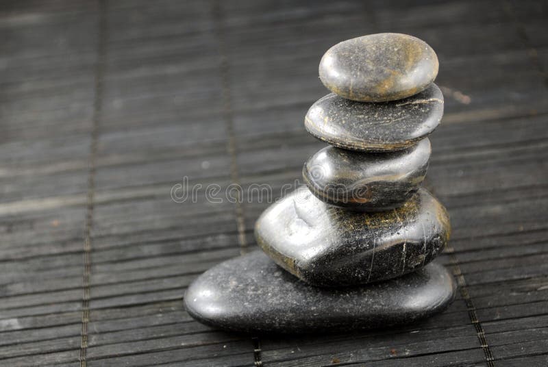 Black zen stones on bamboo stock photo. Image of wellness 21873448