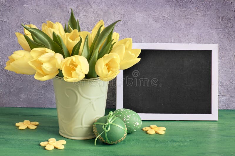 Blackboard with caption \'Happy Easter\' with yellow tulips and green Easter eggs stock image