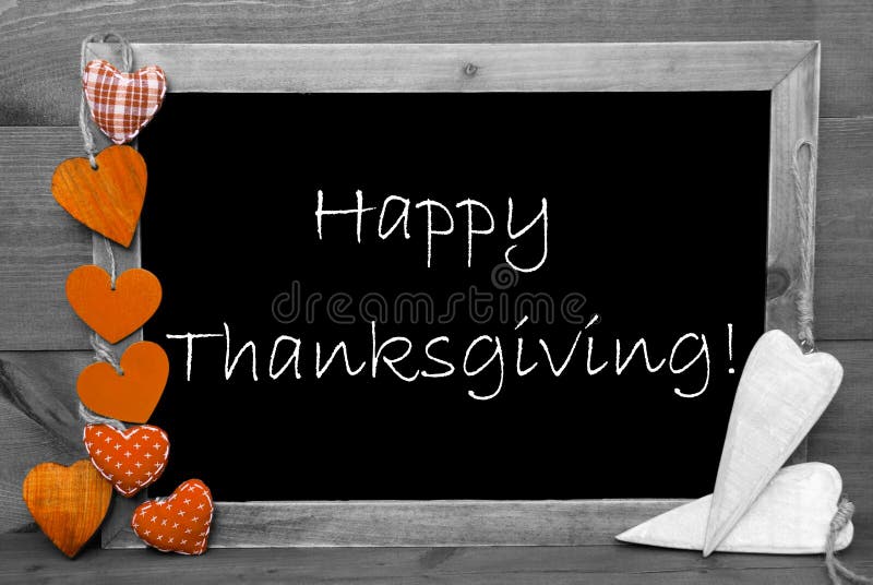 Chalkboard With English Text Happy Thanksgiving. Orange Hearts. Wooden Background With Vintage, Rustic Or Retro Style. Black And White Image With Colored Hot Spots. Chalkboard With English Text Happy Thanksgiving. Orange Hearts. Wooden Background With Vintage, Rustic Or Retro Style. Black And White Image With Colored Hot Spots.