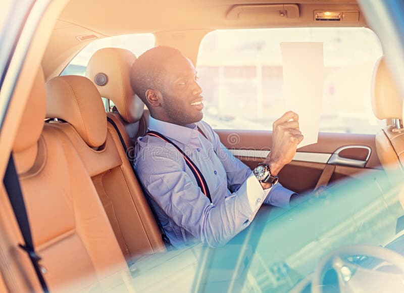 Blackman dans une chemise bleue se repose sur le siège arrière du ` s de voiture image libre de droits Blackman dans une chemise bleue se repose sur le siège arrière du ` s de voiture image libre de droits