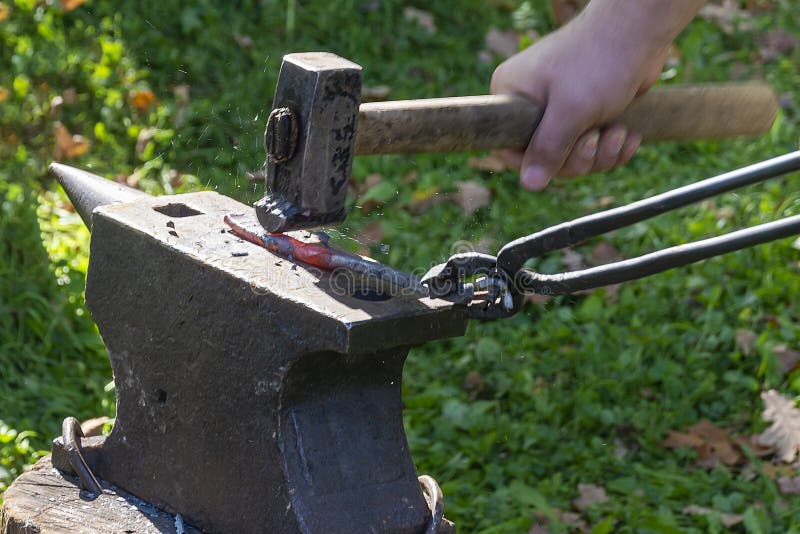 A blacksmith forges hot metal with a hammer on the anvil. The concept of manual labor, crafts, skills. Selective focus stock photo A blacksmith forges hot metal with a hammer on the anvil. The concept of manual labor, crafts, skills. Selective focus stock photo