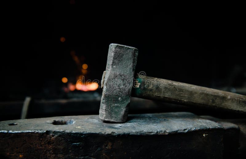 Blacksmith hammer on the anvil against the background of fire