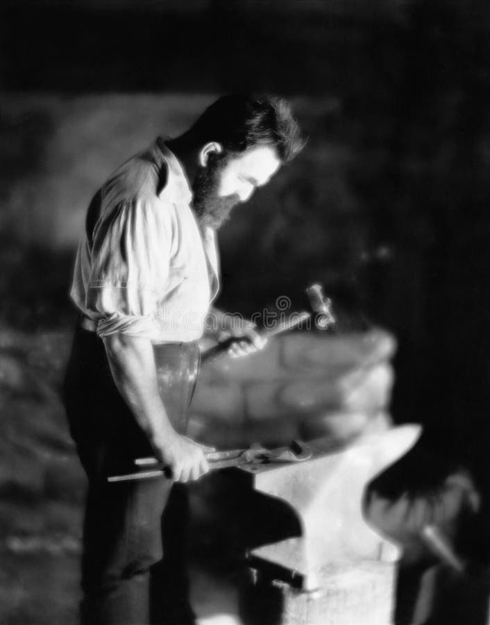 Blacksmith working metal on anvil royalty free stock photo