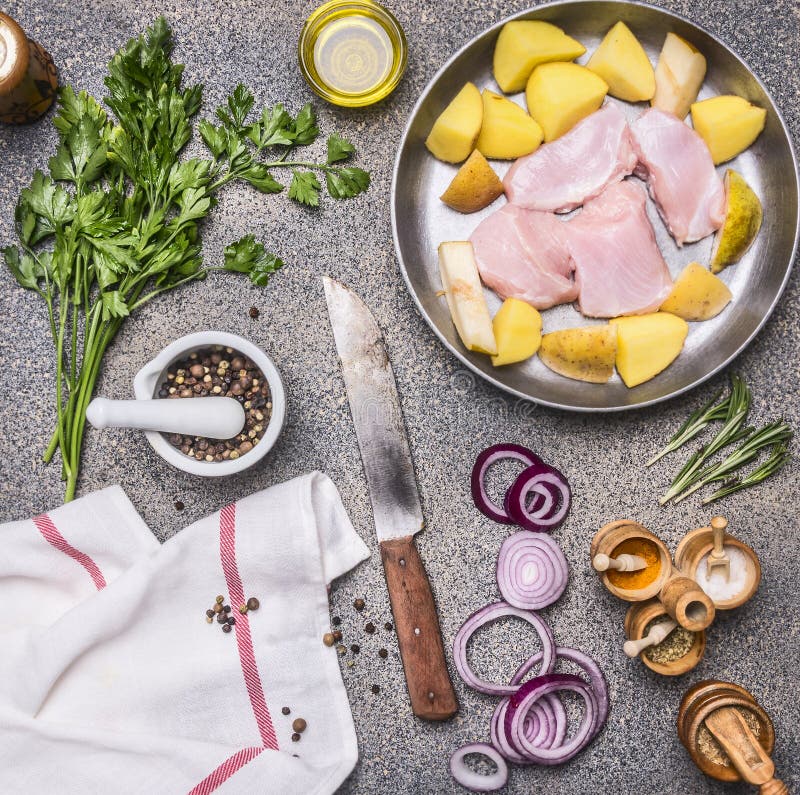 Blanc de dinde cru avec la pomme de terre, la poire, l'oignon rouge et les herbes, avec un grand choix de condiments, couteau de images stock Blanc de dinde cru avec la pomme de terre, la poire, l'oignon rouge et les herbes, avec un grand choix de condiments, couteau de images stock